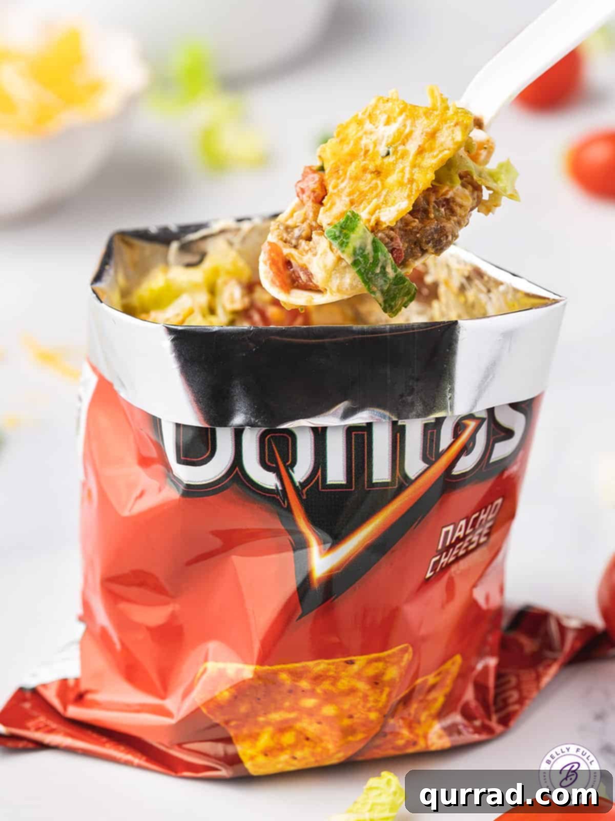 Walking Tacos feature all of your favorite taco ingredients and toppings in a personal-sized bag of chips. Quick and easy to prepare! A fork scooping out a bite from a taco in a bag