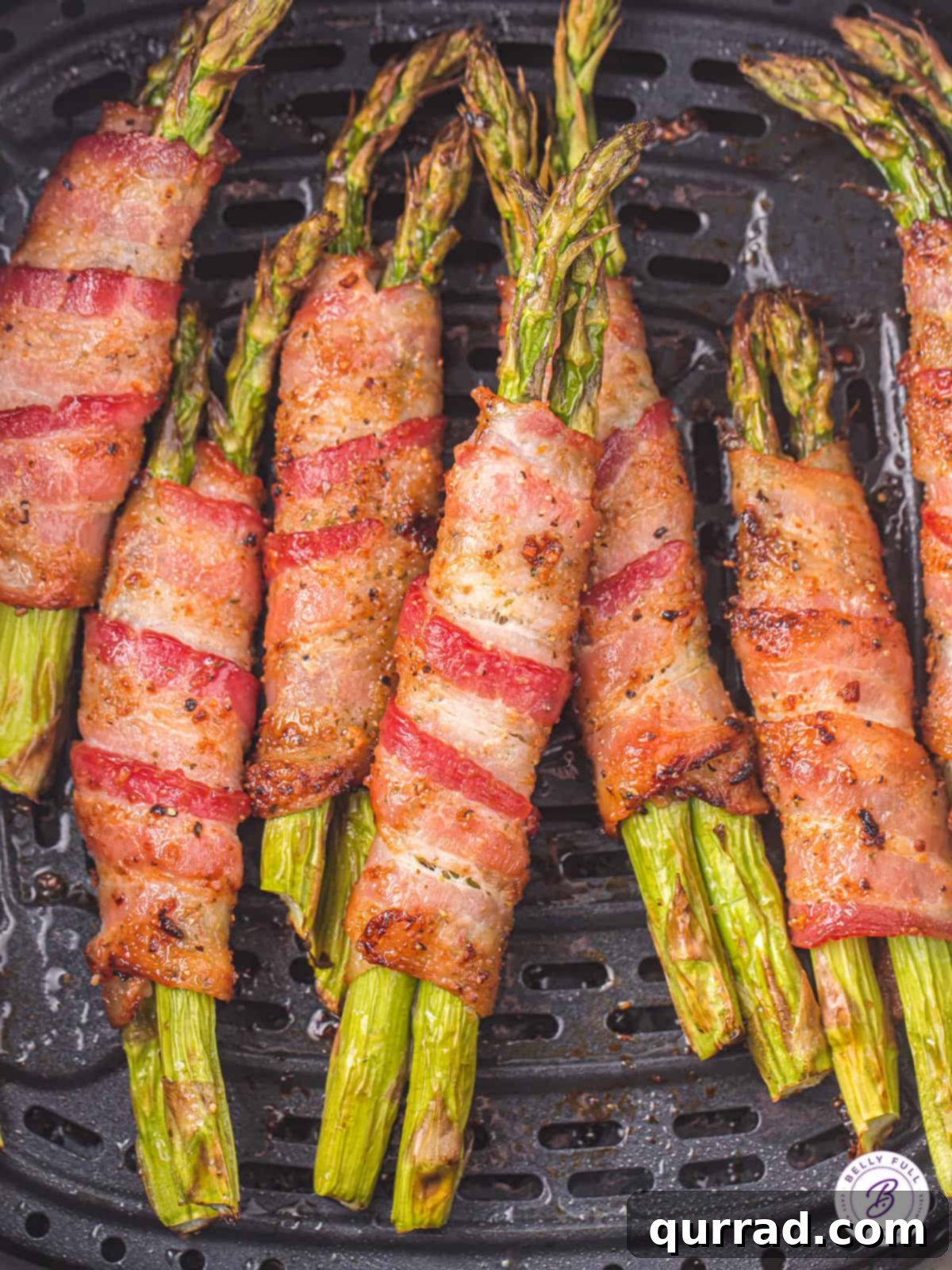 Air Frying Bacon Wrapped Asparagus for Perfect Crispness Bacon wrapped asparagus cooking in the air fryer basket