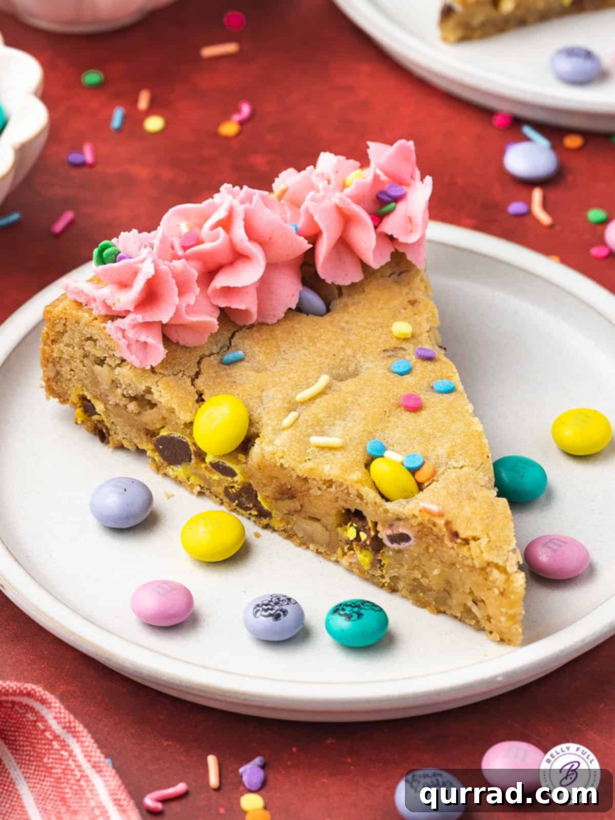 A slice of Easter cookie cake with pink frosting and sprinkles on a white plate, ready to be enjoyed.