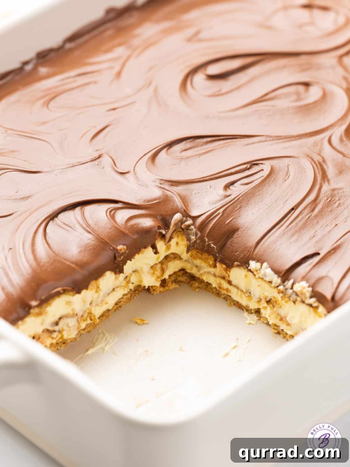 This Chocolate Eclair Dessert tastes like the best combination of Boston cream pie and a chocolate eclair. Just 5 ingredients! A slice of the finished Chocolate Eclair Cake has been removed from the baking dish, revealing the perfectly set layers and inviting texture.