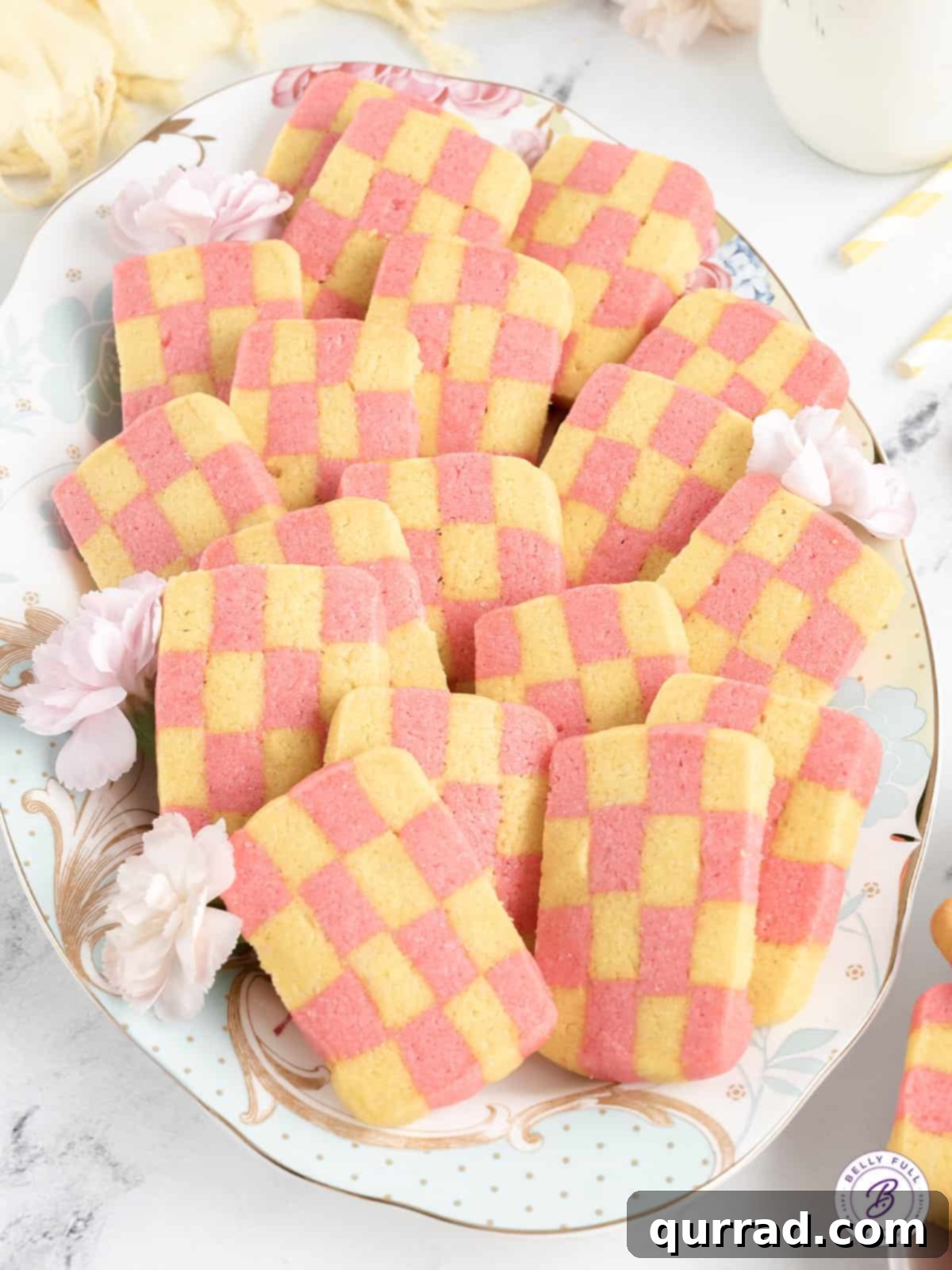 These fun Checkerboard Icebox Cookies are perfect for springtime or Easter and look so impressive on a buffet table. Overhead view of a stack of freshly baked checkerboard icebox cookies arranged artfully on a white plate, highlighting their crisp edges and distinct patterns.