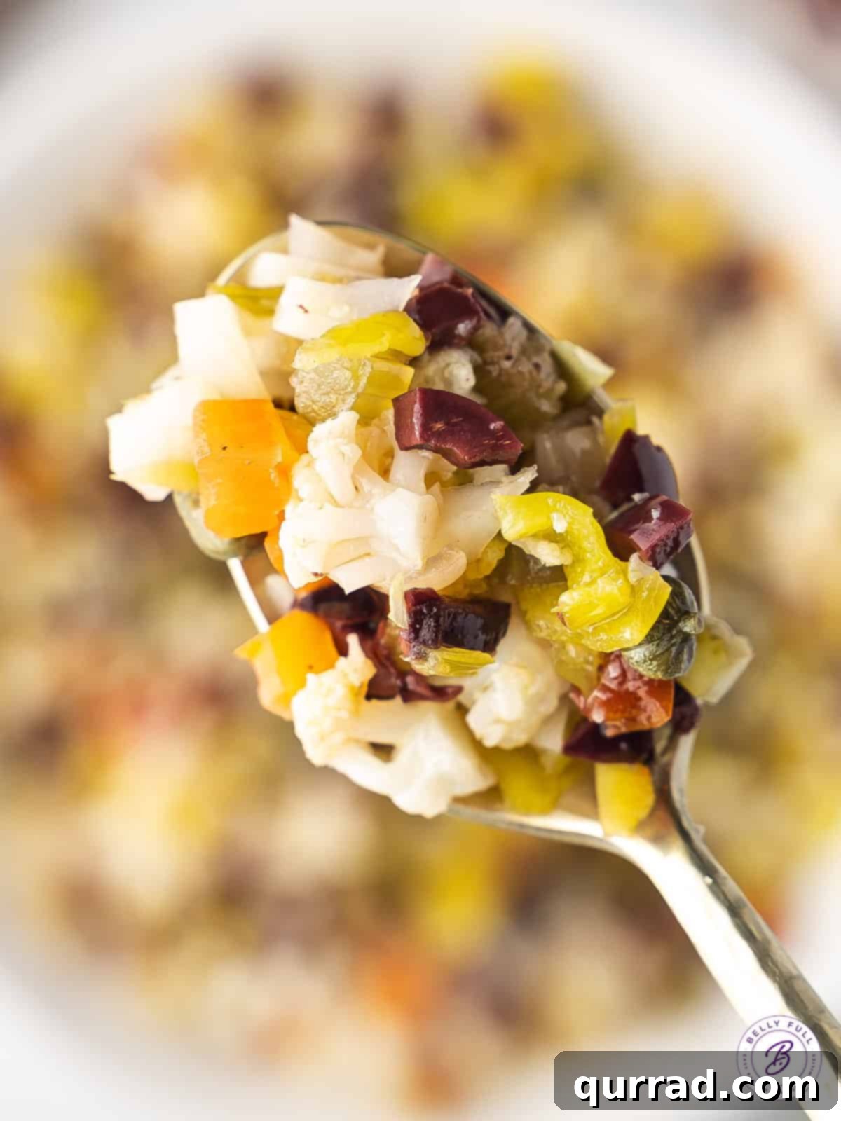 A perfect spoonful of homemade olive salad, ready to be enjoyed. Close up of a spoonful of olive salad, showing its chunky texture and vibrant colors.