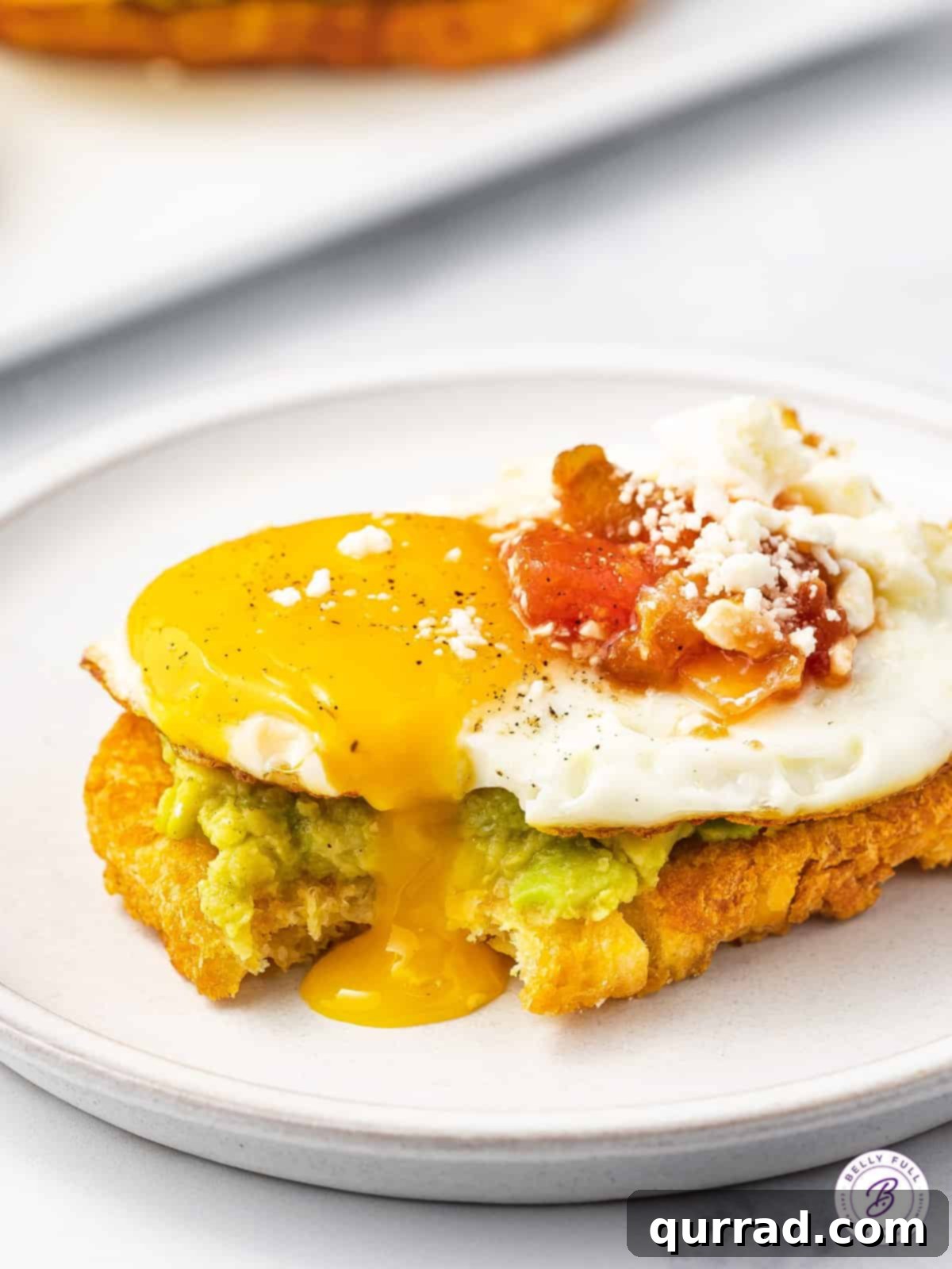 Hash Brown Avocado Toast with a runny fried egg yolk adding richness