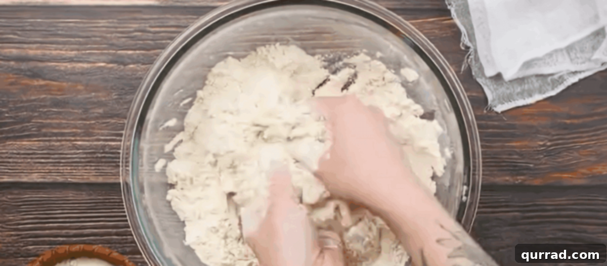 Hands combining the lard and flour in a glass bowl to form fine crumbs for tortilla dough.