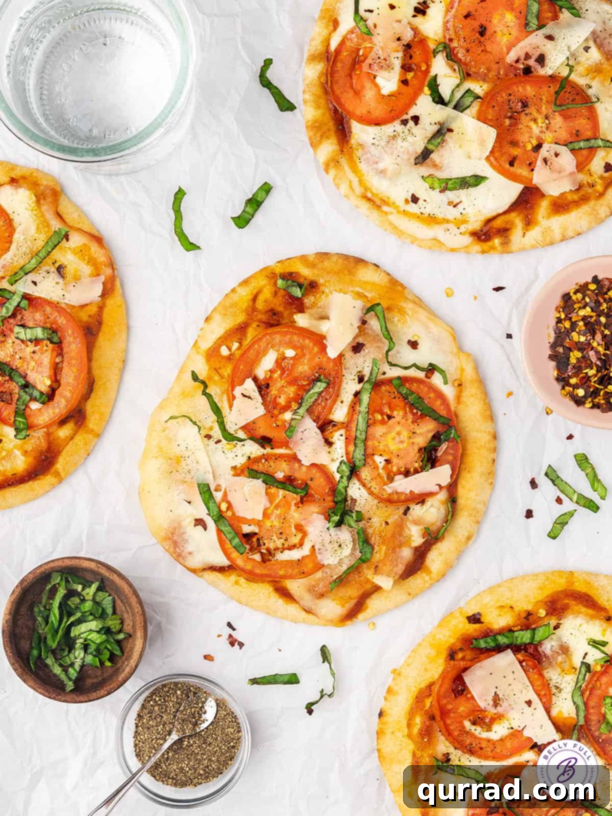 Deliciously simple Air Fryer Margherita Pita Pizzas ready in minutes. Overhead view of two finished margherita pita pizzas, garnished with fresh basil.