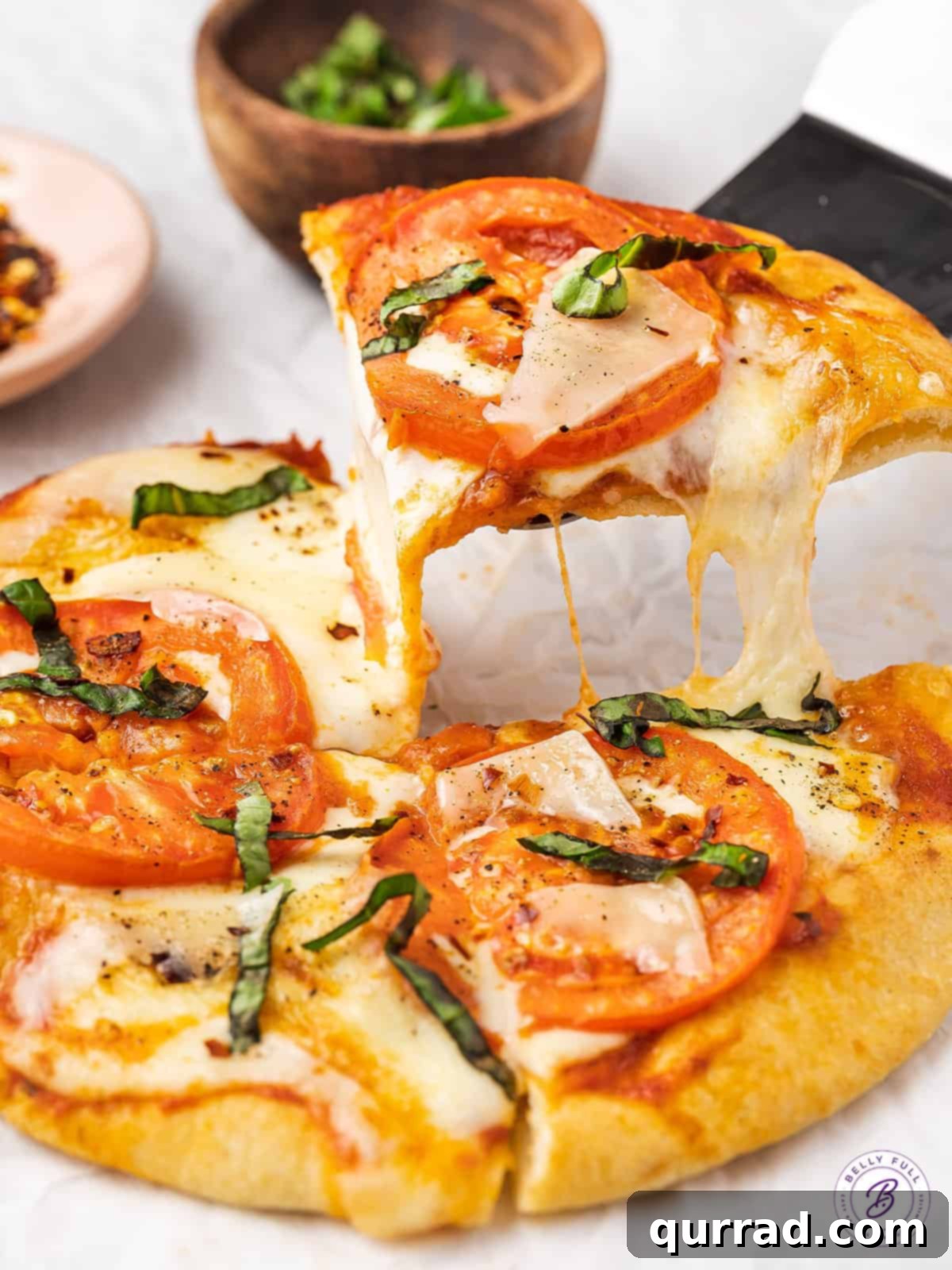 Perfectly cooked Air Fryer Margherita Pita Pizza ready to be enjoyed. A spatula serving a slice of pita margherita pizza, showing its crispy crust.