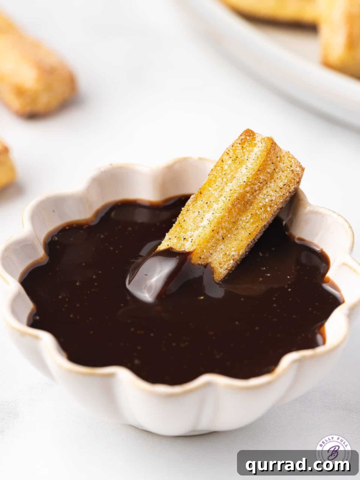 Indulgent delight: Air Fryer Churro Bites with chocolate sauce A golden air fryer churro bite dipped into a luscious bowl of chocolate sauce