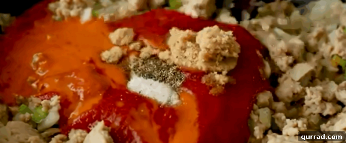 Buffalo Chicken Sandwich Mess 5 Adding the sauce ingredients including tomato sauce, buffalo sauce, and brown sugar to the cooked ground chicken and vegetables.