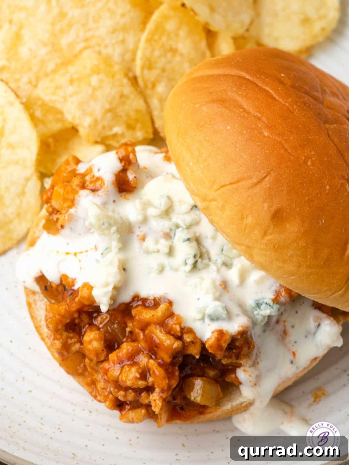Buffalo Chicken Sandwich Mess 7 Overhead view of a Buffalo chicken sloppy joe on a plate with potato chips as a side.