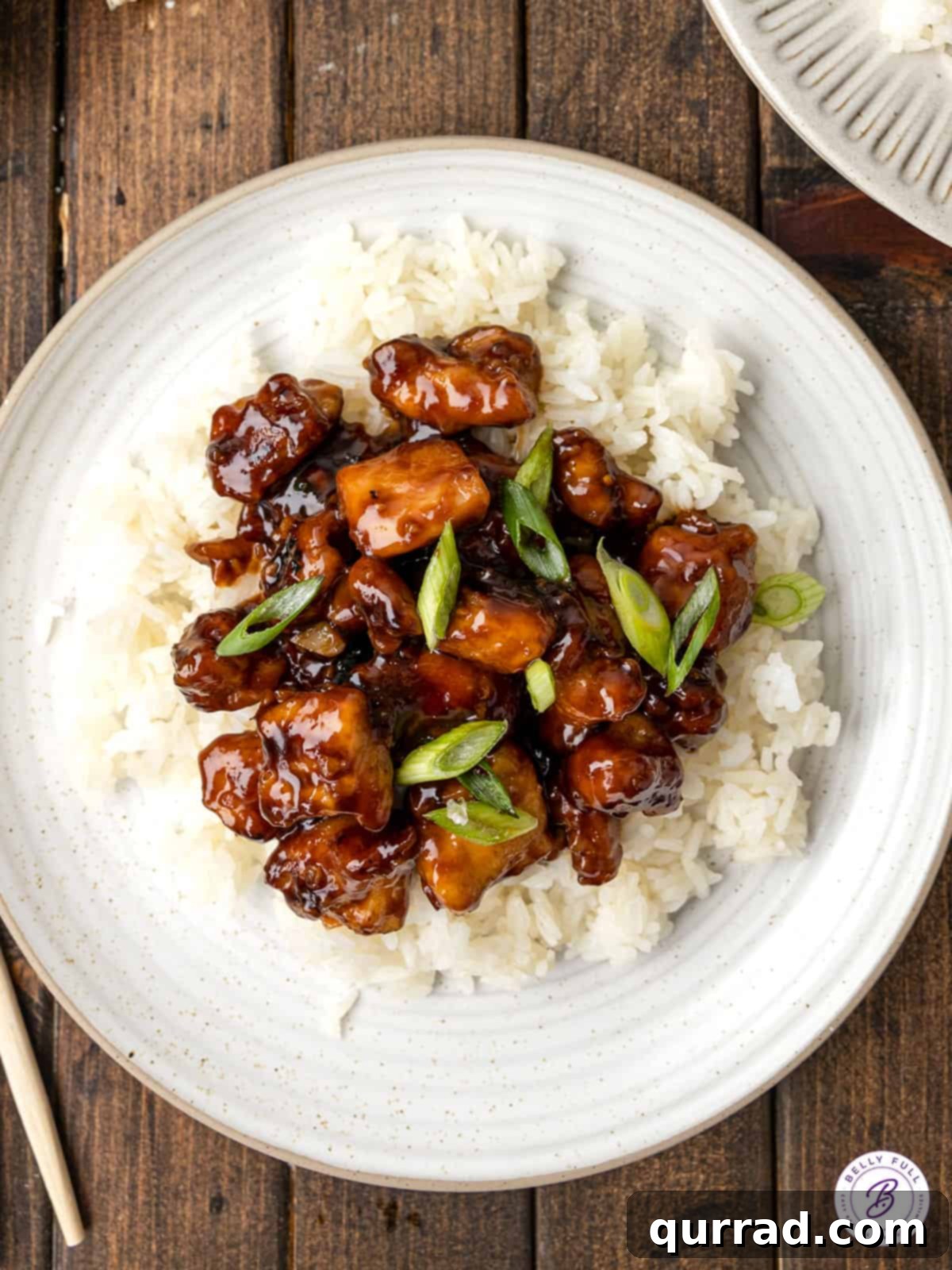 Classic Bourbon Chicken Served Over Rice for a Complete Meal Overhead view of a perfectly plated bowl of homemade bourbon chicken served over fluffy white rice, garnished with fresh scallions, ready to be enjoyed.