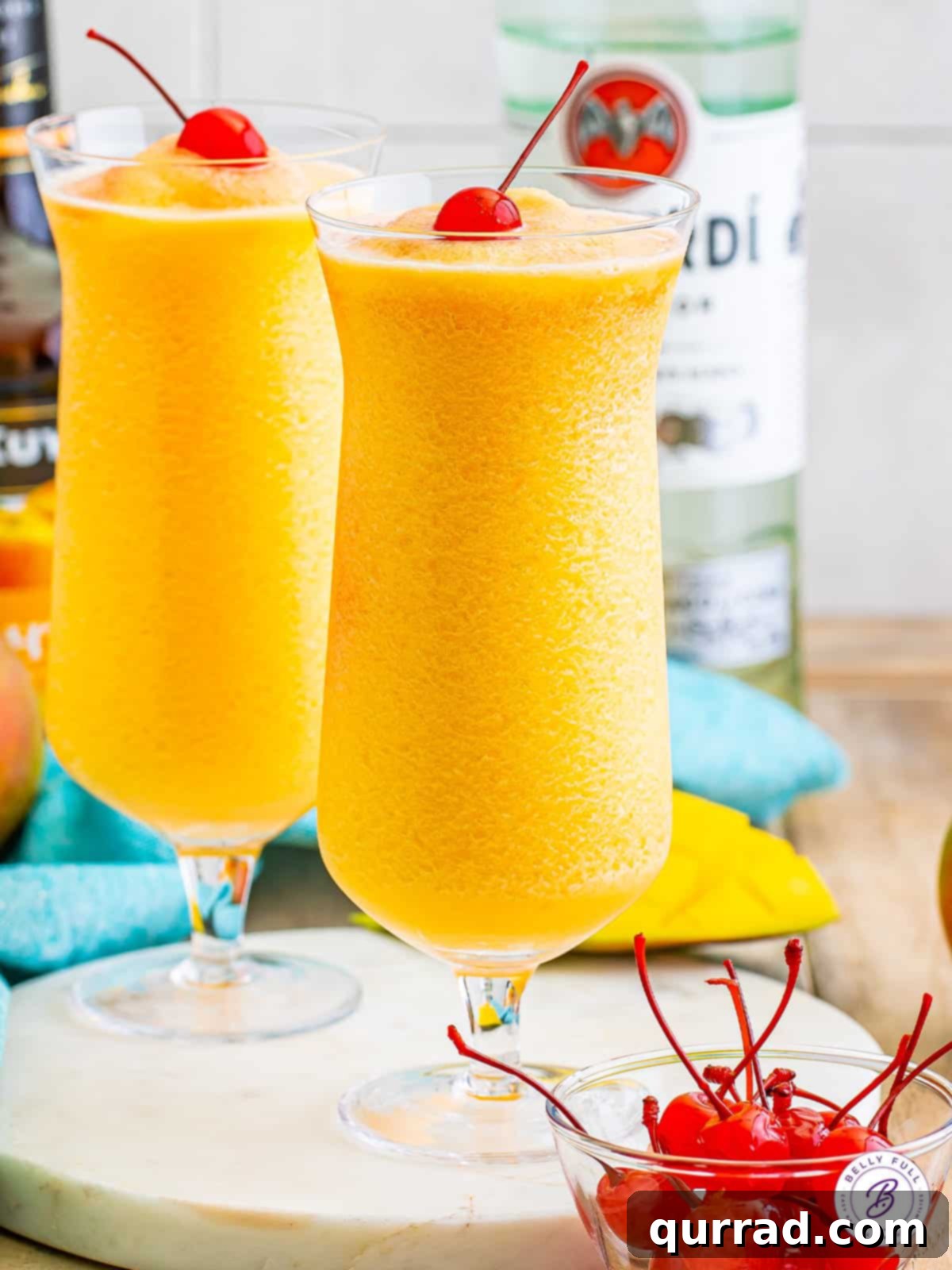 Kiss on the Lips Drink: A Carnival Cruise Line Copycat with Peach Schnapps, White Rum, Mango Mixer, and Grenadine. Two vibrant Kiss on the Lips drinks, garnished with bright red maraschino cherries, evoke a sense of tropical delight and summer refreshment. They are made with peach schnapps, white rum, mango mixer, and grenadine, just like the iconic Carnival Cruise cocktail.