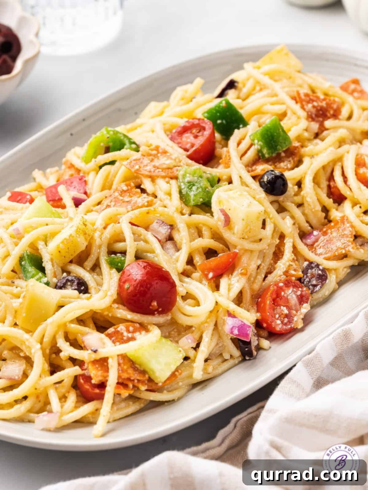 Chilled spaghetti salad: A refreshing and delicious dish for any meal. An inviting angled view of a serving plate filled with chilled spaghetti pasta salad, ready to be enjoyed.