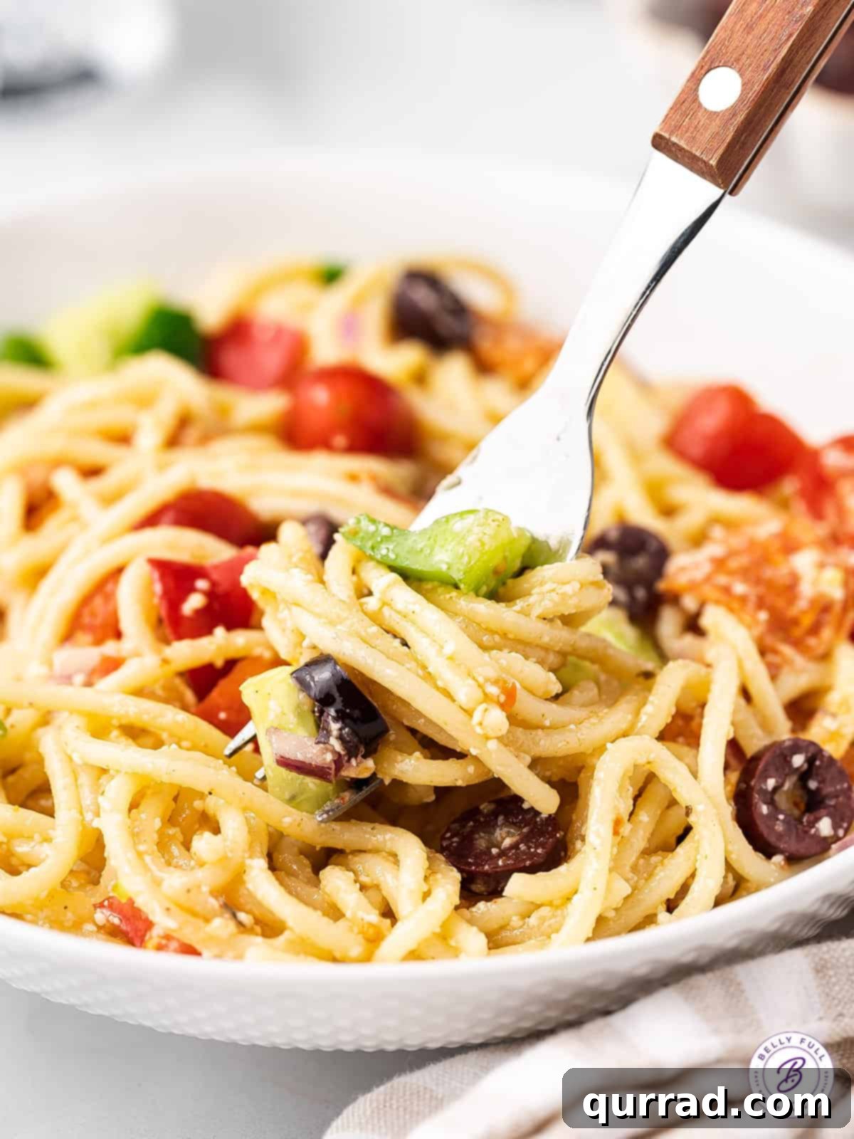 Spaghetti Salad: A delightful mix of pasta, pepperoni, cheese, and fresh greens. A fork twirling spaghetti pasta salad, ready to be enjoyed