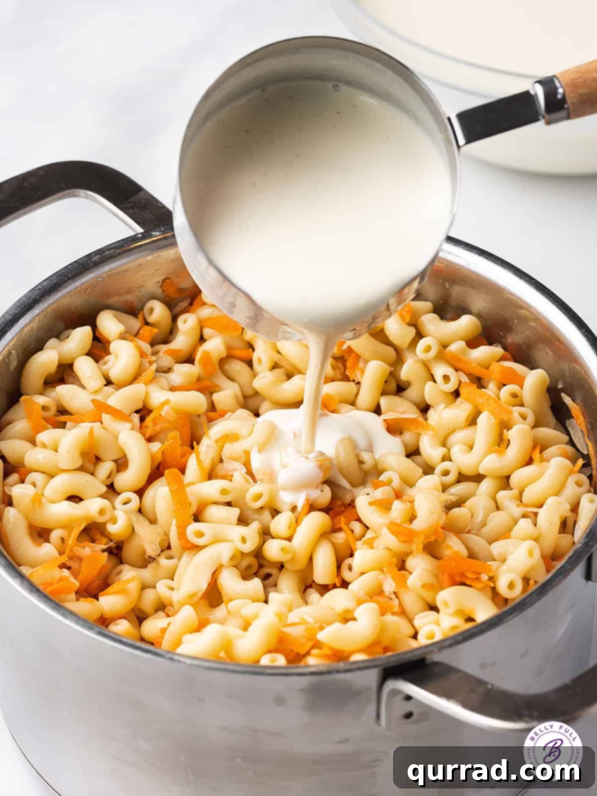 This Hawaiian Macaroni Salad recipe is made with grated carrot and onion, then coated in a creamy dressing that’s a bit tangy and sweet. Pouring rich, creamy dressing over the prepared macaroni and vegetable mixture for the Hawaiian Macaroni Salad