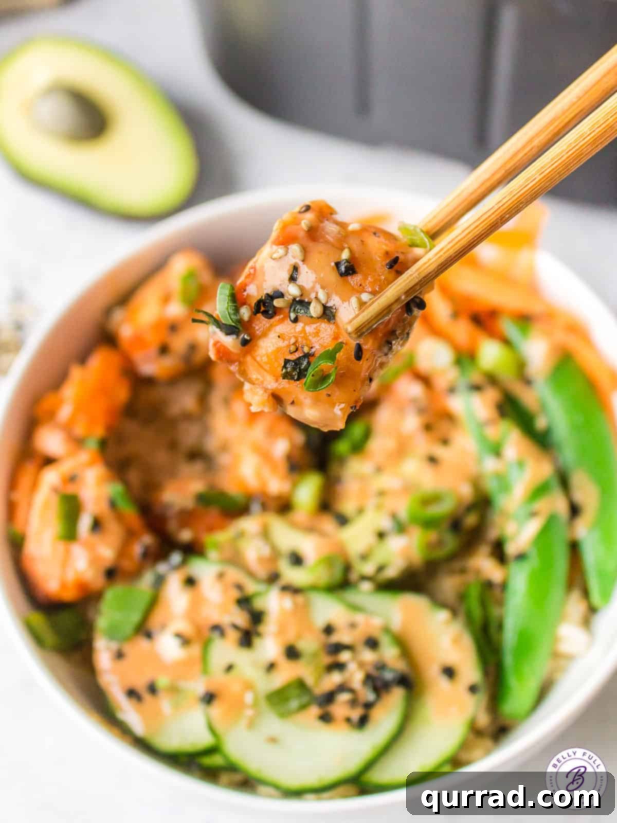 Savoring Air Fryer Salmon Bowls: Flavor & Convenience Close-up of chopsticks holding a perfectly cooked piece of air fryer salmon from a rice bowl, ready to be enjoyed