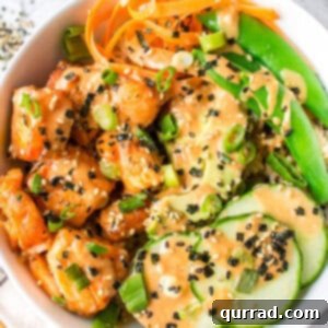 Overhead view of a salmon bowl with cucumbers, carrots, and snap peas