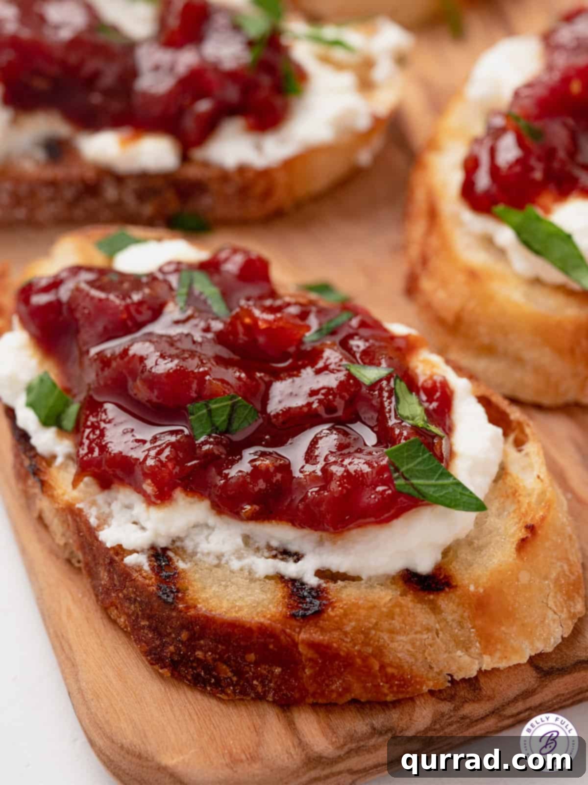 Close up shot of a crostini topped with creamy cheese and a spoonful of homemade tomato jam.