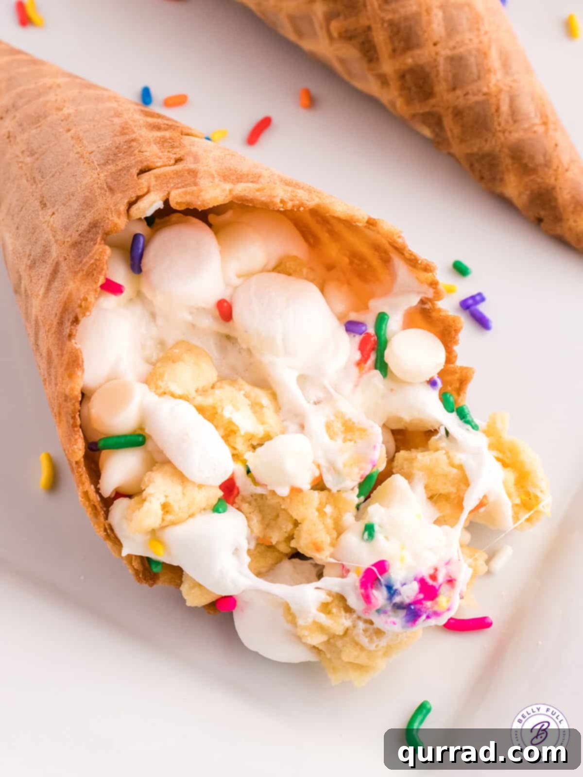 A close-up of a waffle cone stuffed with marshmallows, white chocolate chips, and sugar cookies, looking incredibly tempting! Close up of a deliciously gooey sugar cookie campfire cone