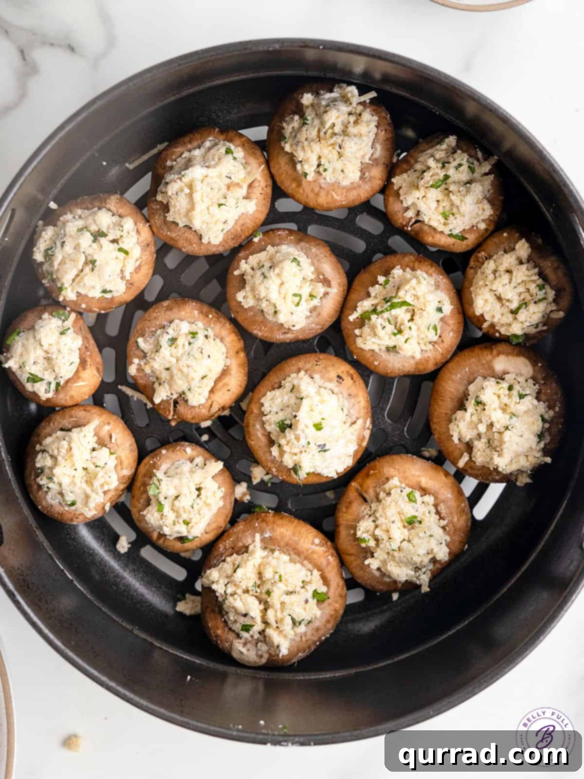 Golden brown stuffed mushrooms cooking in an air fryer. Stuffed mushrooms cooking in an air fryer basket