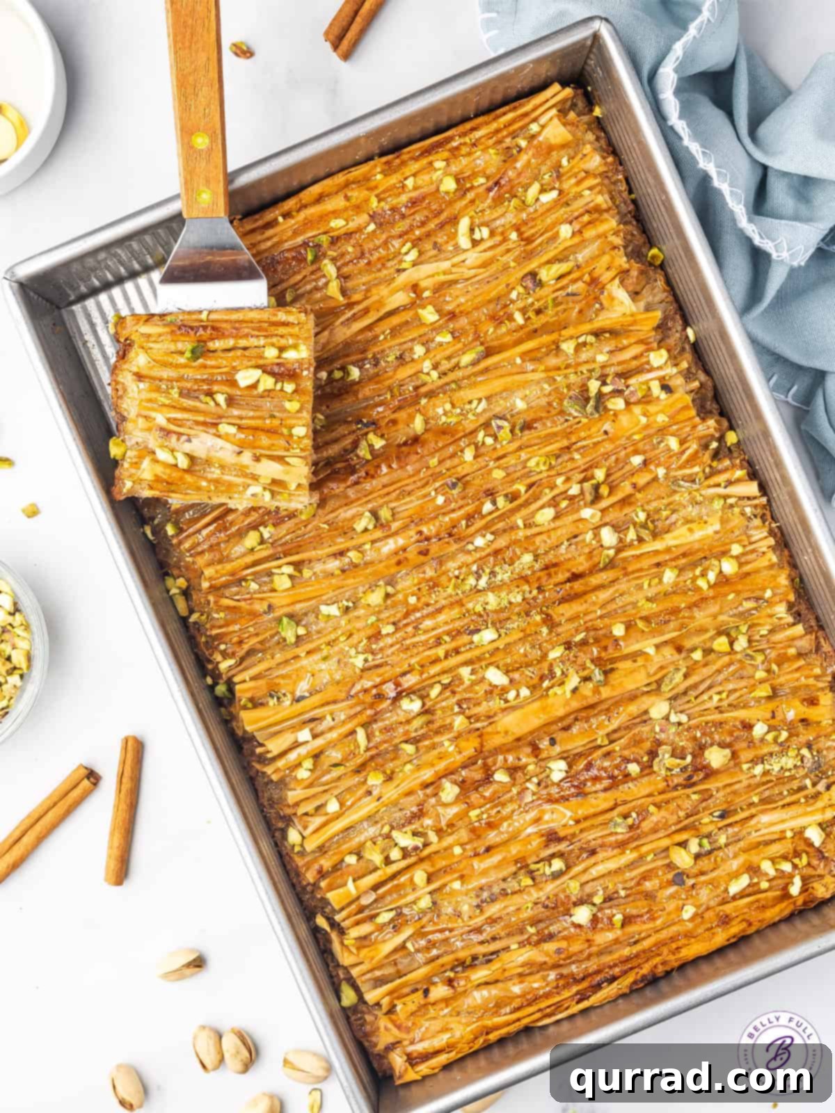 Crinkled Phyllo Delight 3 pan of baked Muakacha with piece on serving spatula