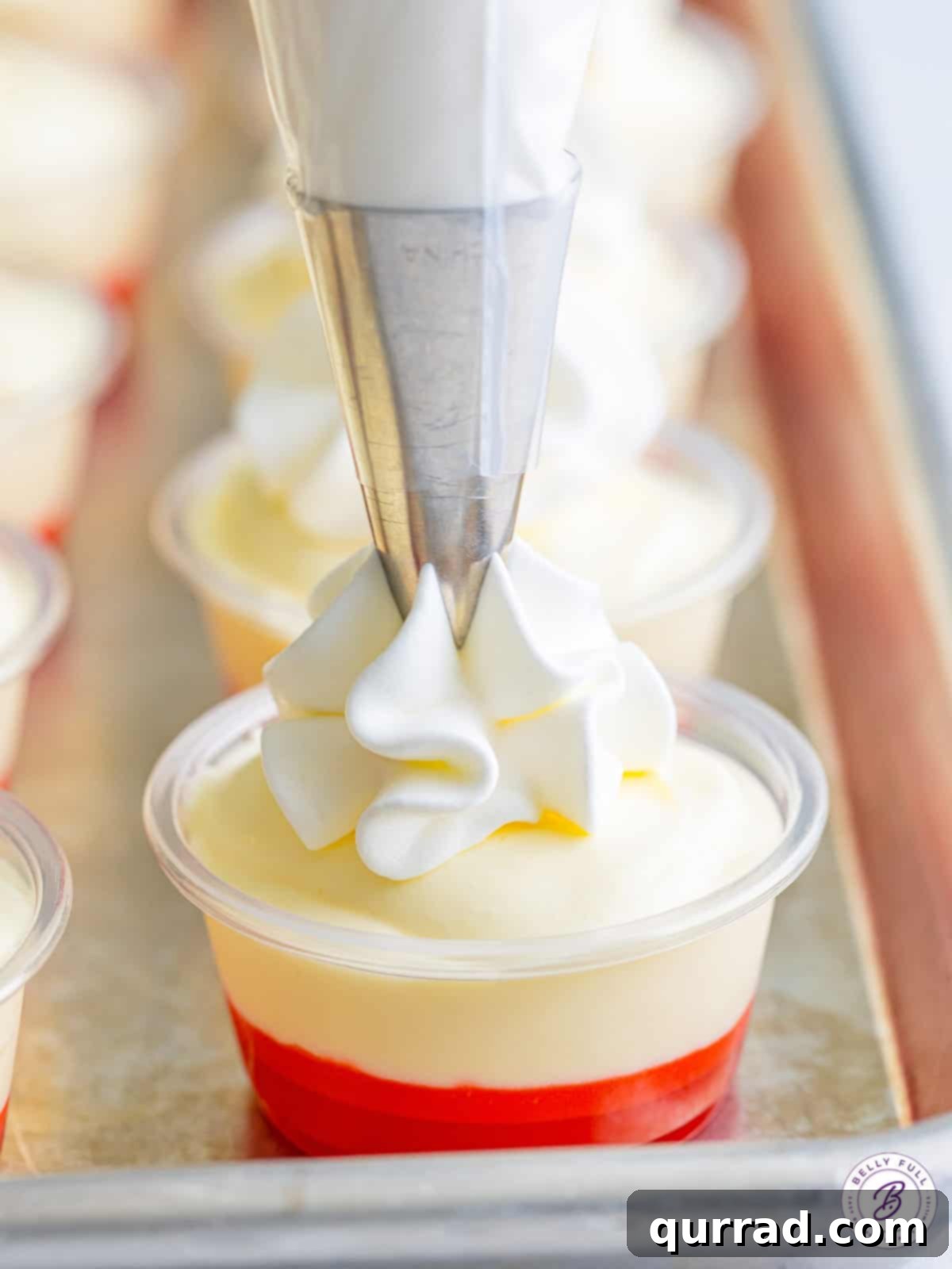 Strawberry Banana Dream Shots 4 whipped cream being piped on top of banana pudding shots