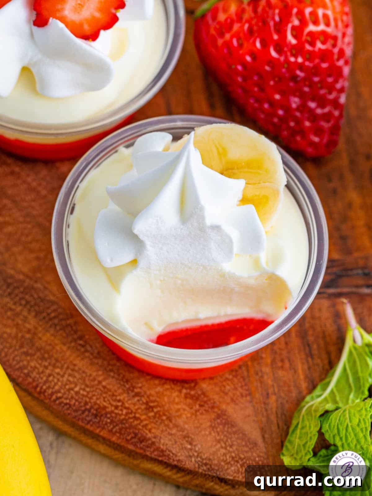 Strawberry Banana Dream Shots 5 a strawberry banana pudding shot with a bite taken out, showing the layers