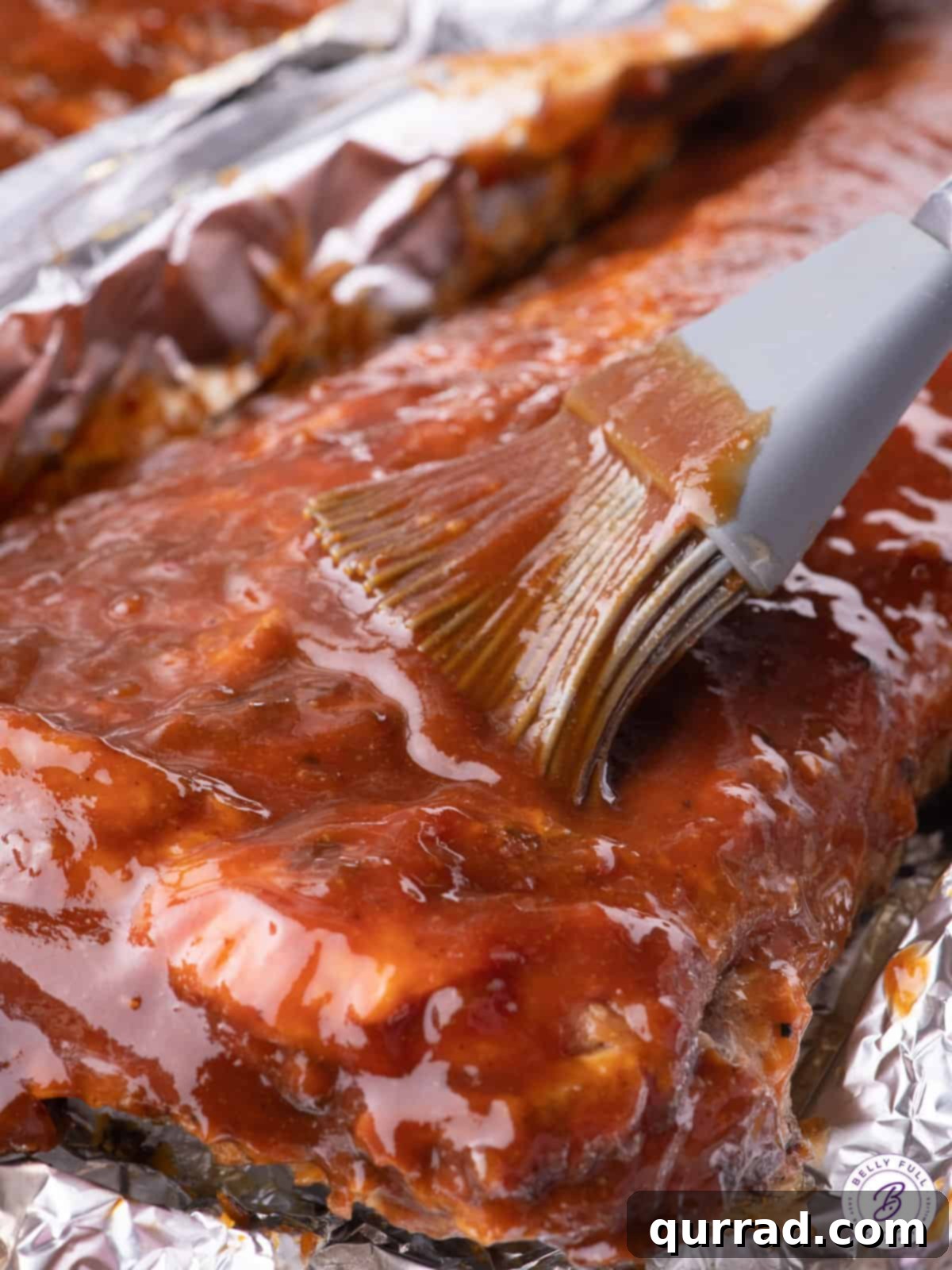 Bourbon BBQ sauce being slathered on a rack of ribs, showing its glossy finish.
