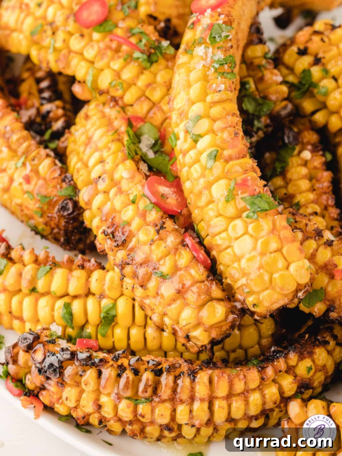 Addictive Air Fryer Corn Ribs 2 A pile of air fryer corn ribs on a plate, garnished with fresh herbs and chili flakes