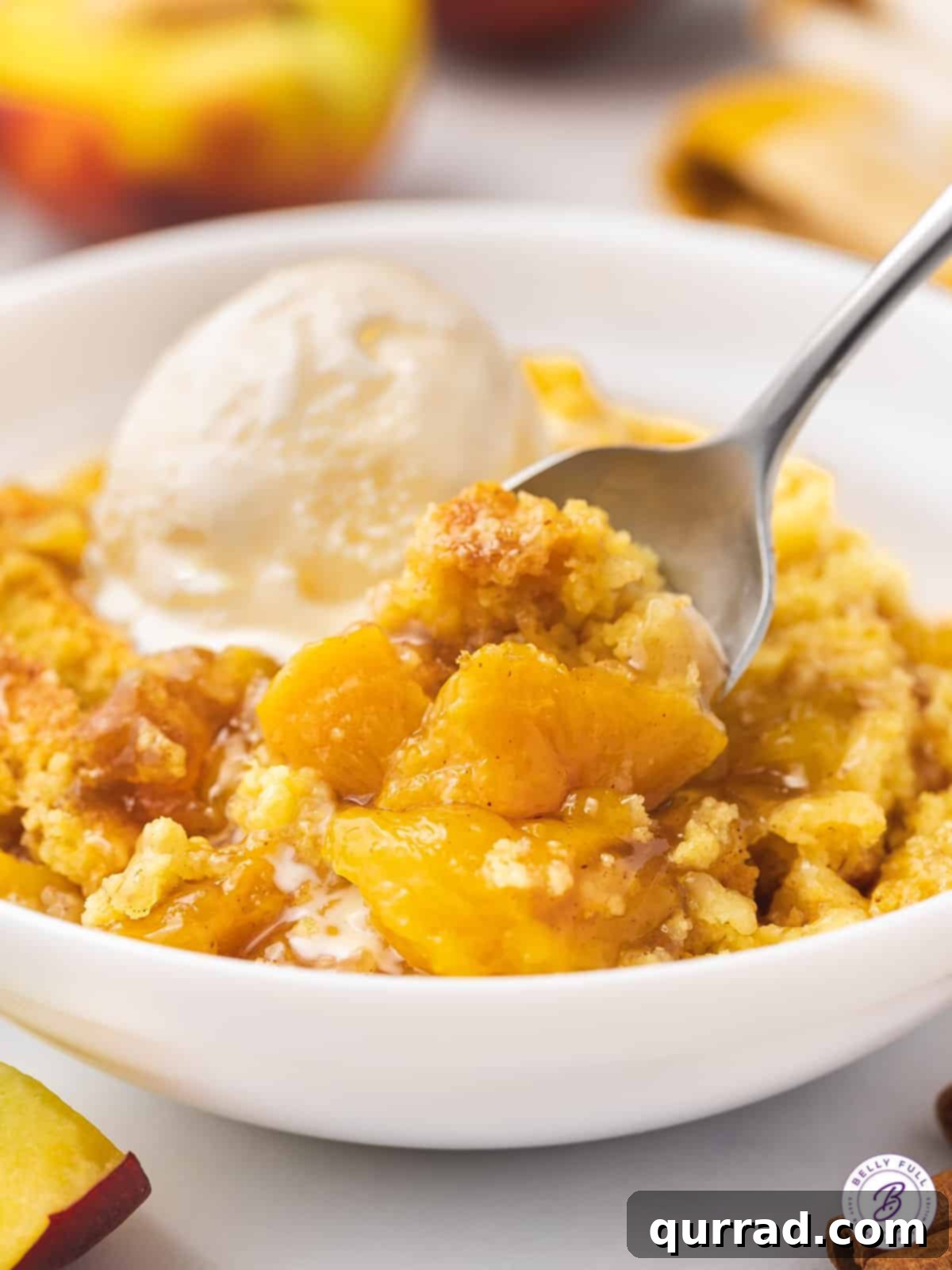 Lazy Peach Cobbler 6 A close-up shot of a bowl of warm Peach Dump Cake with a scoop of melting vanilla ice cream and a spoon, ready to be enjoyed.