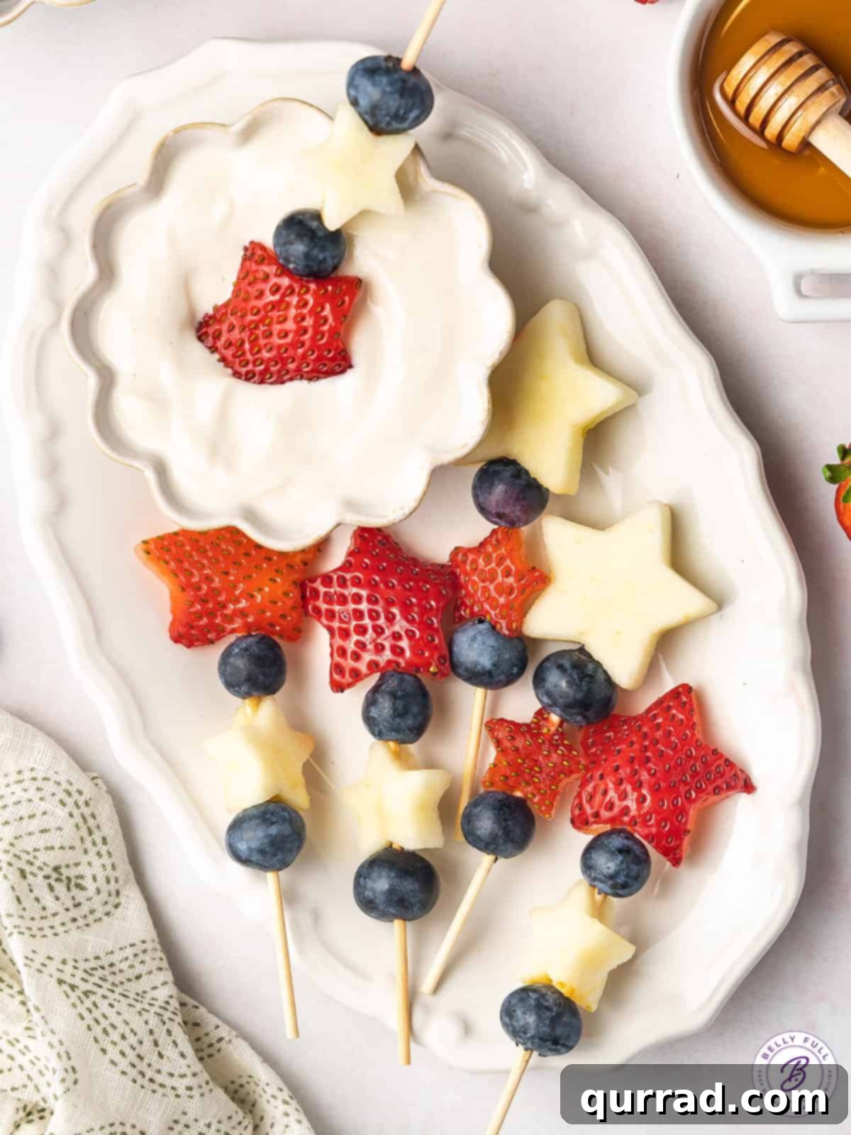 Tricolor Fruit Delights 5 Overhead view of assembled fruit kabobs with apple and strawberry stars and blueberries on a rustic wooden platter.