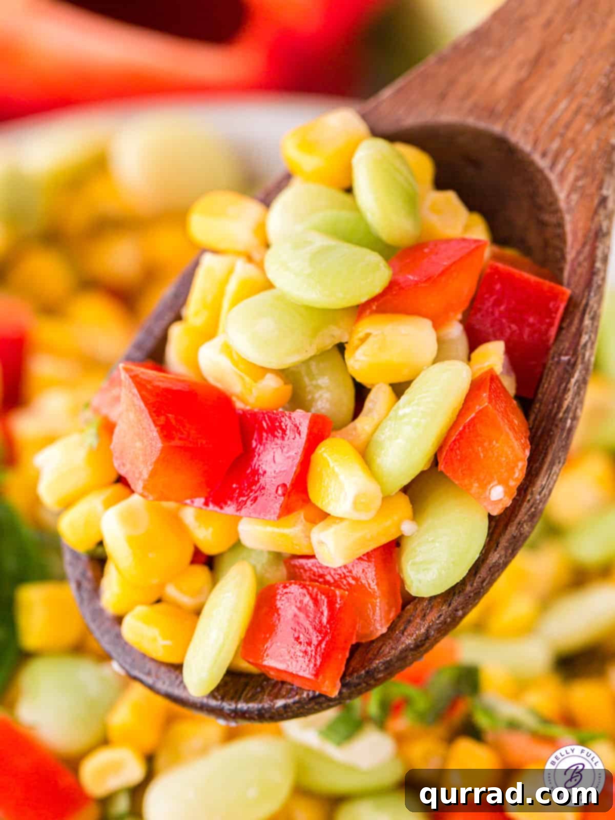 Made with corn, lima beans, and red bell pepper, Corn Succotash is ready in less than 15 minutes. An easy side dish for summer! A wooden spoonful of corn succotash, garnished with fresh basil