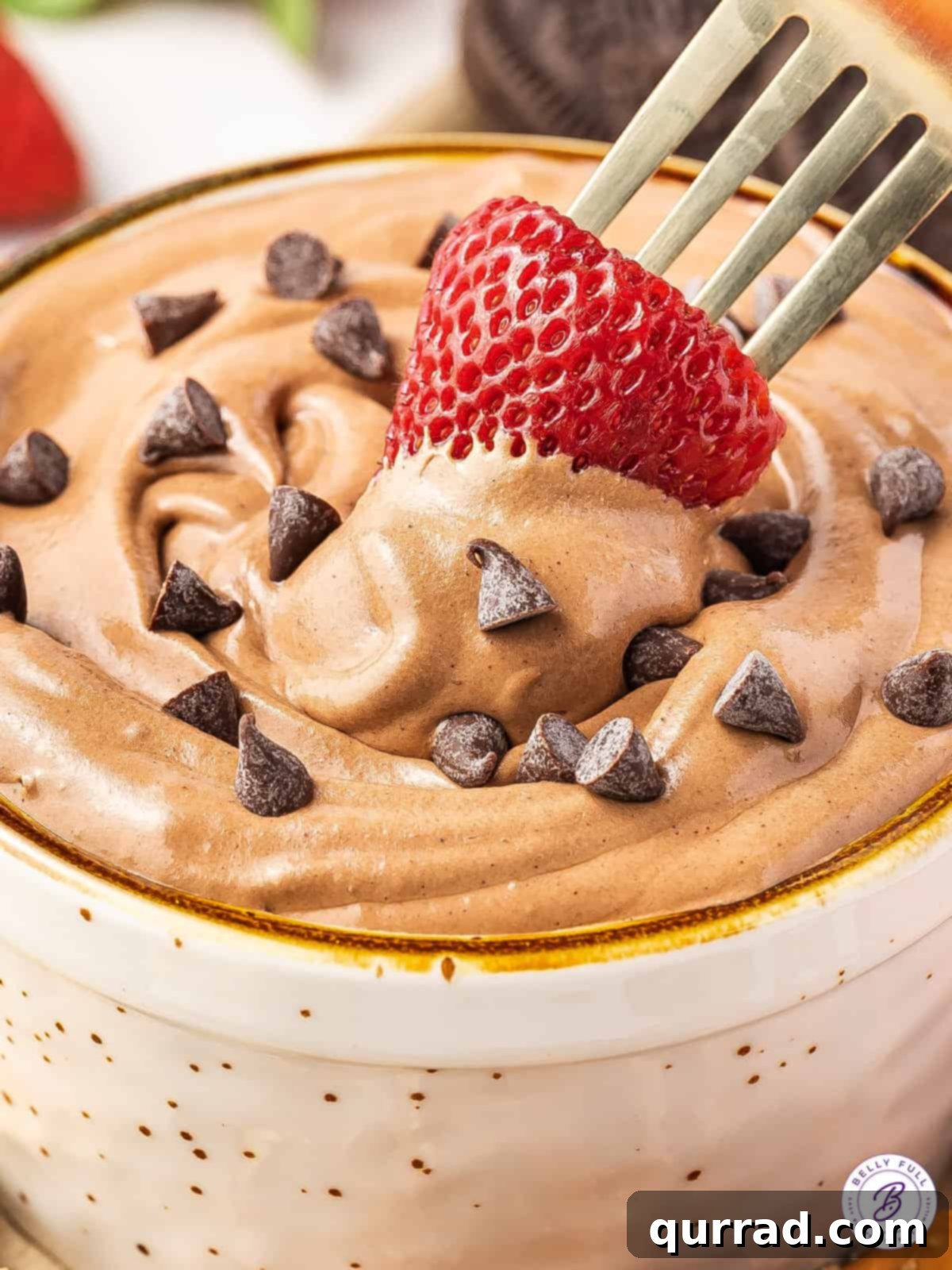 A fork dipping a strawberry into brownie batter dip