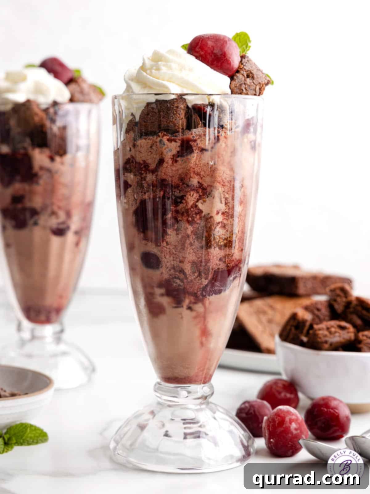 A Pair of Exquisite Black Forest Ice Cream Sundaes Two black forest ice cream sundaes in tall dishes, adorned with whipped cream and a cherry on top.