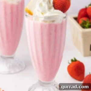 A boozy strawberry milkshake topped with whipped cream and a strawberry