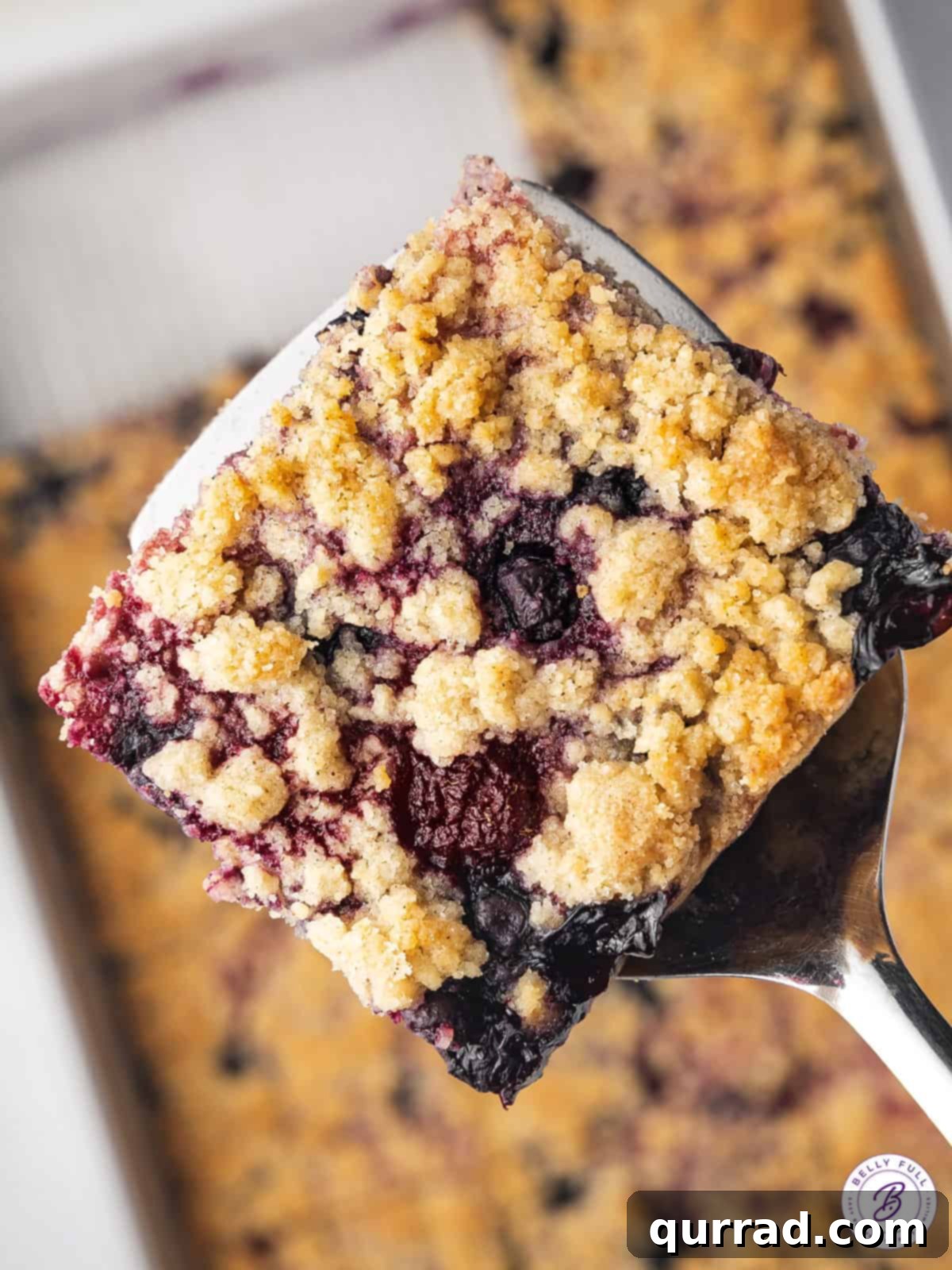 A single raspberry and blueberry crumb bar placed on a spatula, ready to be served
