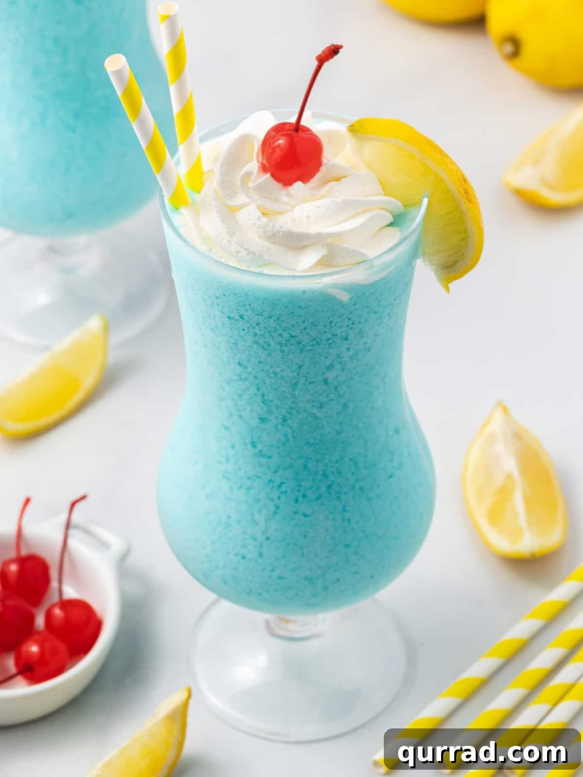 An overhead, angled view of a beautiful Frozen Blue Lagoon drink in a tall glass, highlighting its smooth, icy texture and vibrant blue color.