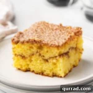 A beautiful square slice of honey bun cake on a pristine white plate, showcasing the layered swirl and vanilla glaze.