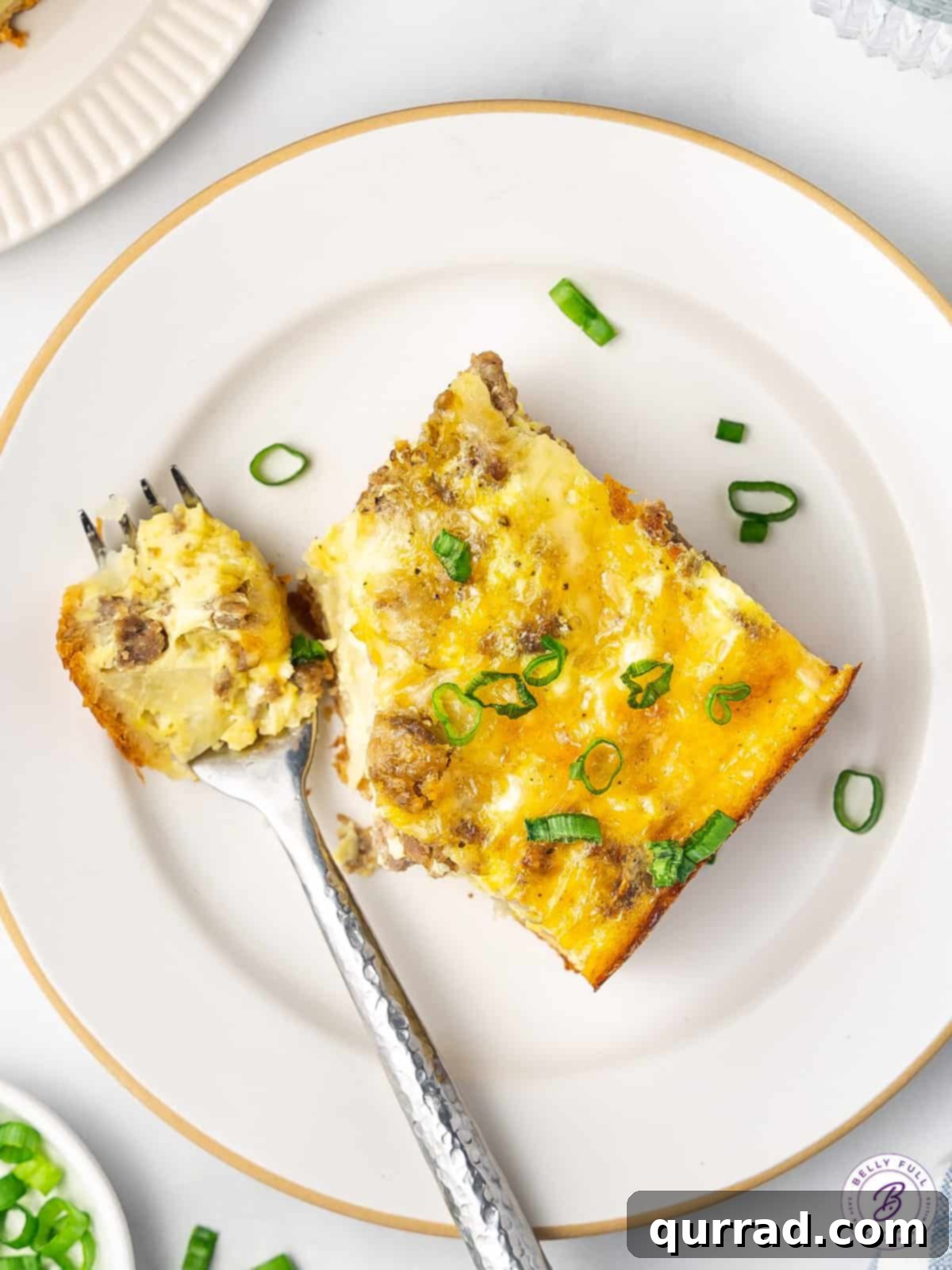 A delicious slice of crescent roll egg bake, revealing layers of eggs, sausage, and hash browns, ready to be enjoyed. Overhead view of a perfectly baked slice of crescent roll egg bake, showcasing its golden crust and savory filling.