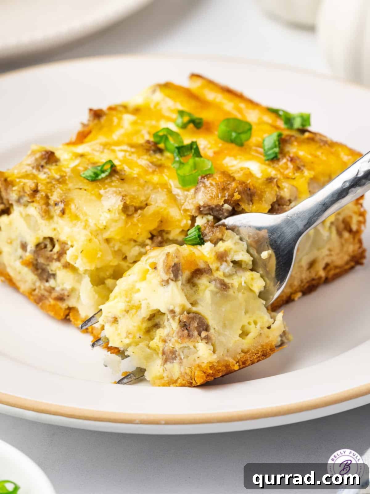 A fork is poised to take a bite out of a delicious square of crescent roll breakfast casserole. A fork piercing a square of golden crescent roll breakfast casserole, ready for a bite.