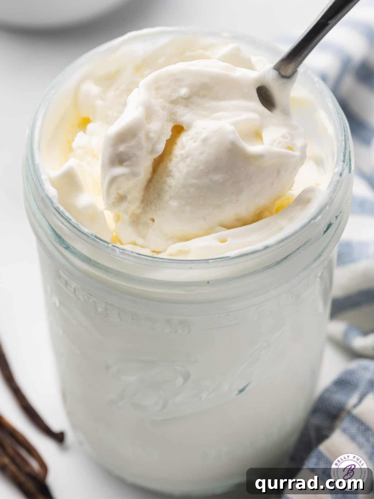 Homemade Jar Ice Cream Bliss 4 A spoon scooping a generous portion of creamy vanilla ice cream from a mason jar, highlighting its perfect texture.