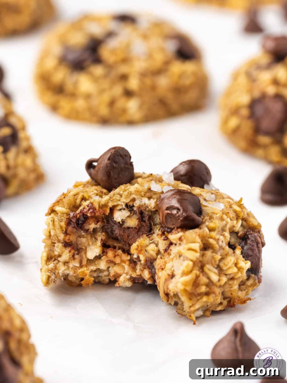 Delicious Banana Oatmeal Cookie, Half Eaten A close-up of a banana oat cookie with a small bite taken out, revealing its soft, chewy interior.
