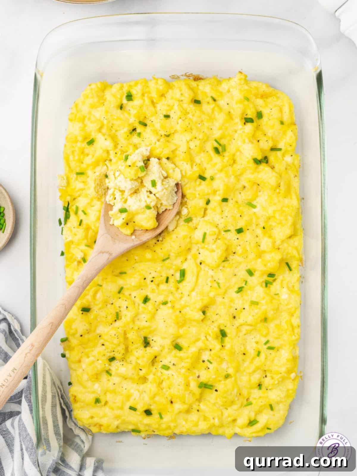 A wooden spoon on a casserole dish of oven baked scrambled eggs