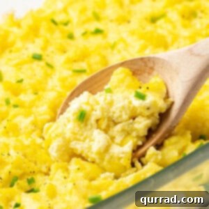 A wooden spoon stirring oven baked scrambled eggs