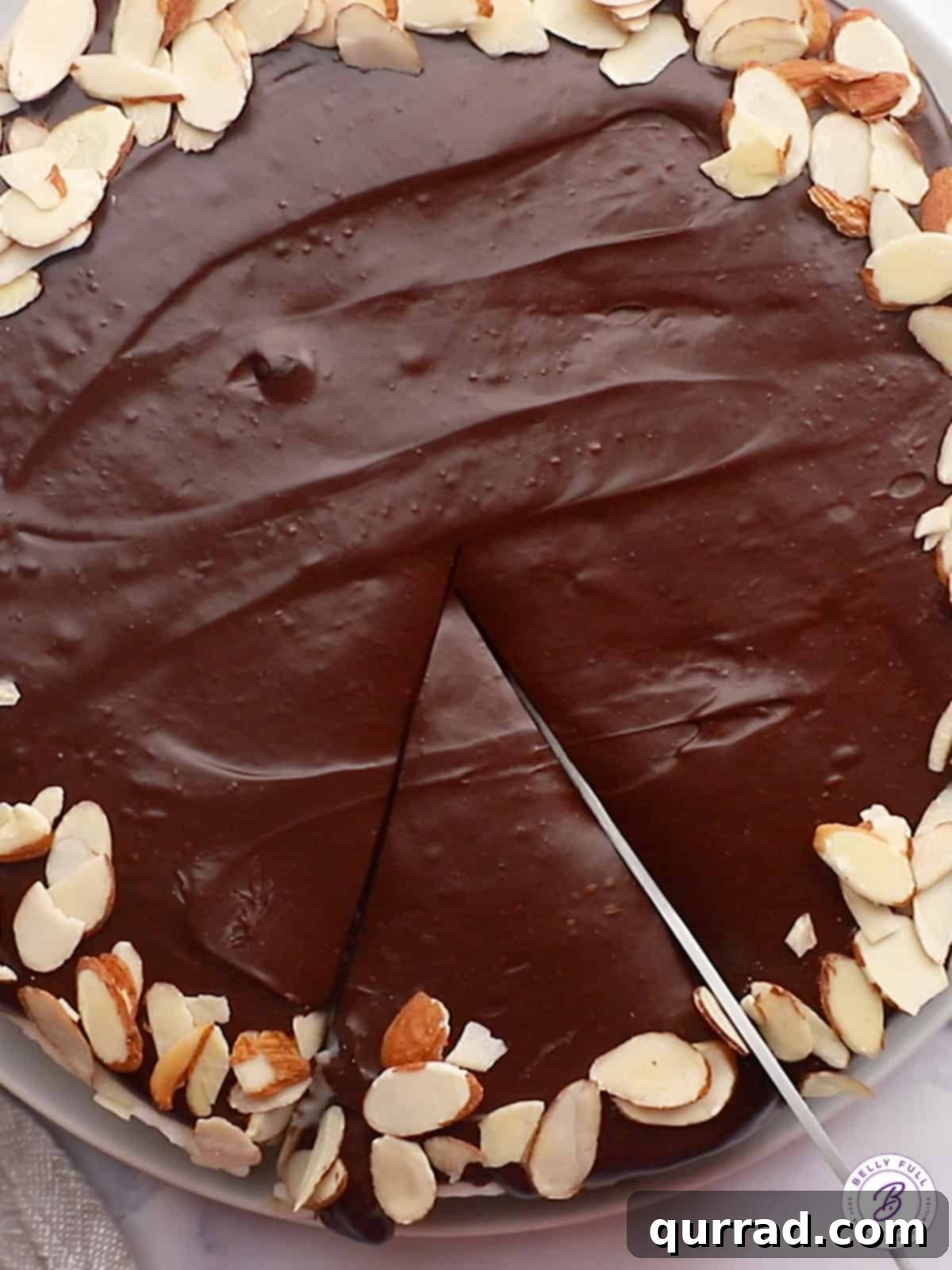 A knife cutting a perfect slice of Almond Joy chocolate cake, revealing the distinct layers and almonds.