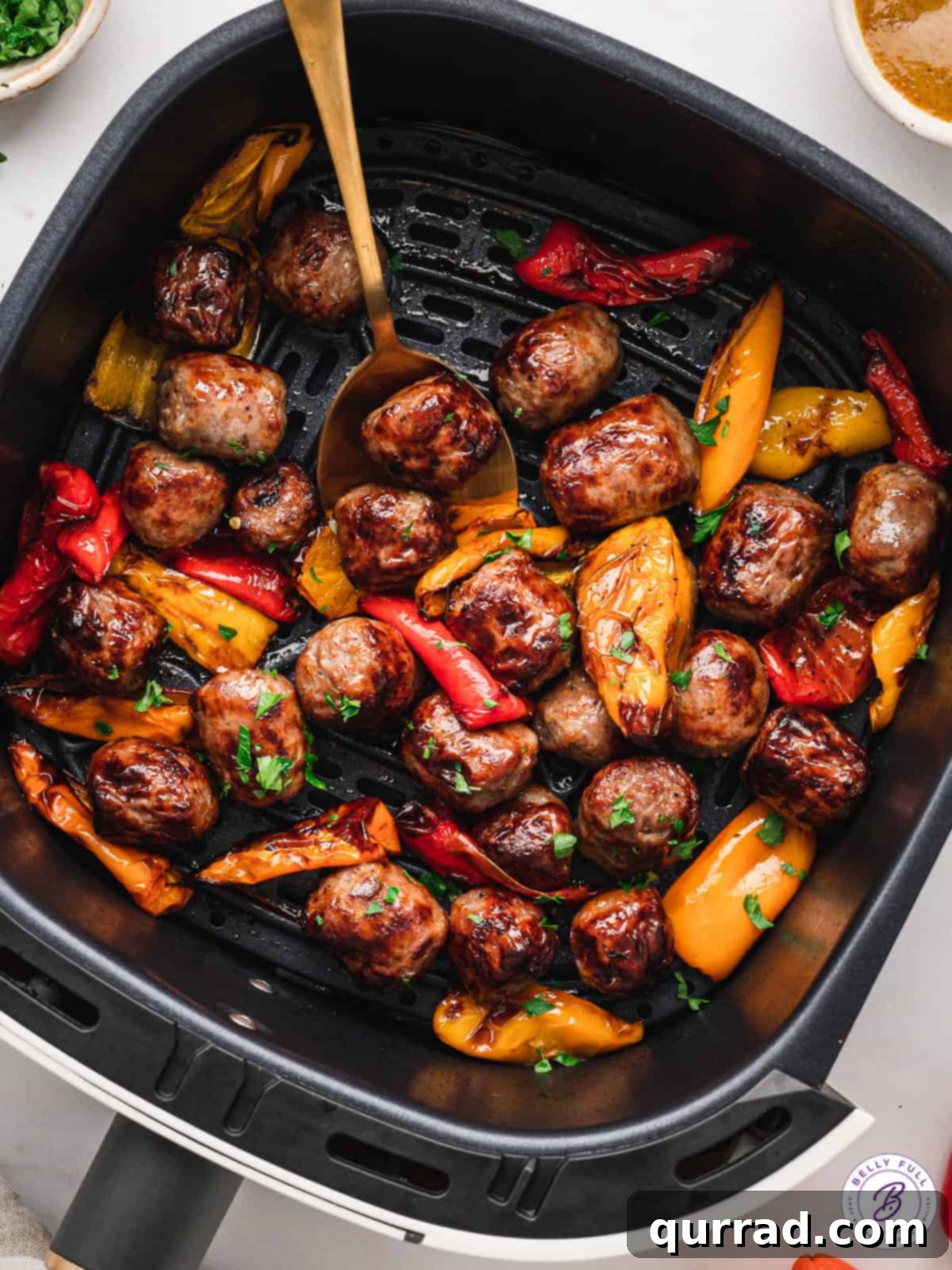 Close-up view of diced bratwurst and sweet peppers perfectly arranged in an air fryer basket, ready for cooking.