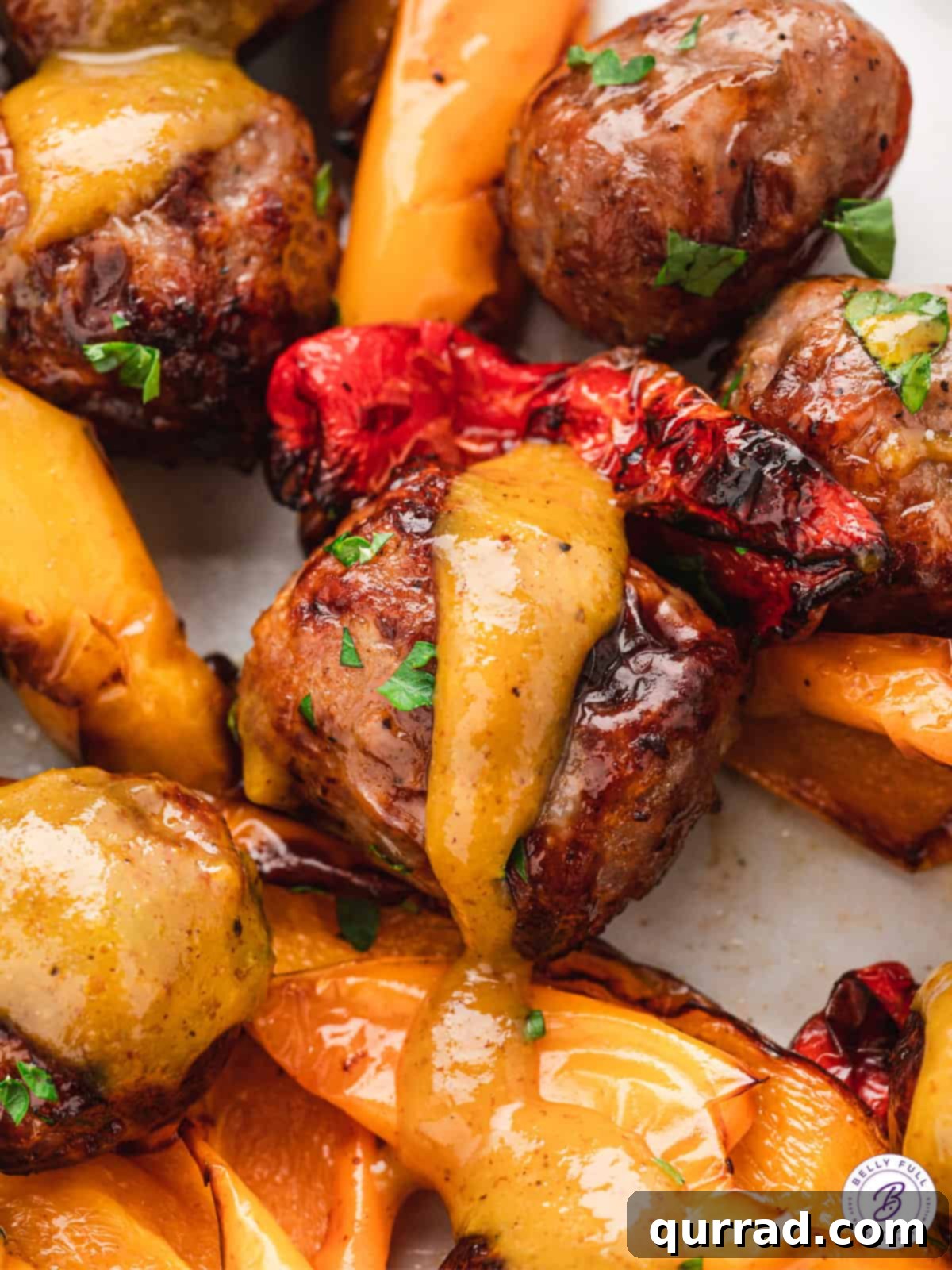 Delicious air fryer brat bites and peppers, generously drizzled with the homemade honey-mustard sauce, ready to be enjoyed.