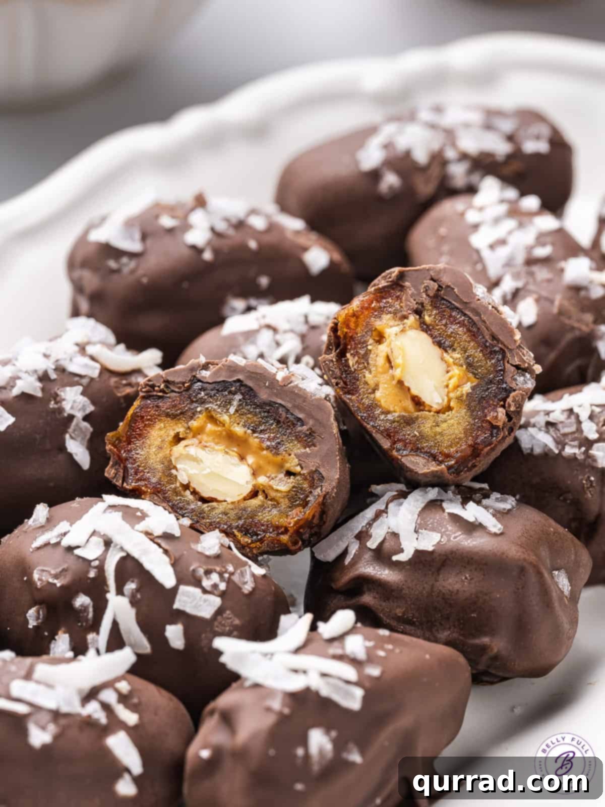A glimpse inside: these Almond Stuffed Dates showcase their healthy, delicious core. A meticulously sliced almond stuffed date reveals its creamy almond butter and whole almond filling, resting on a bed of other prepared dates.