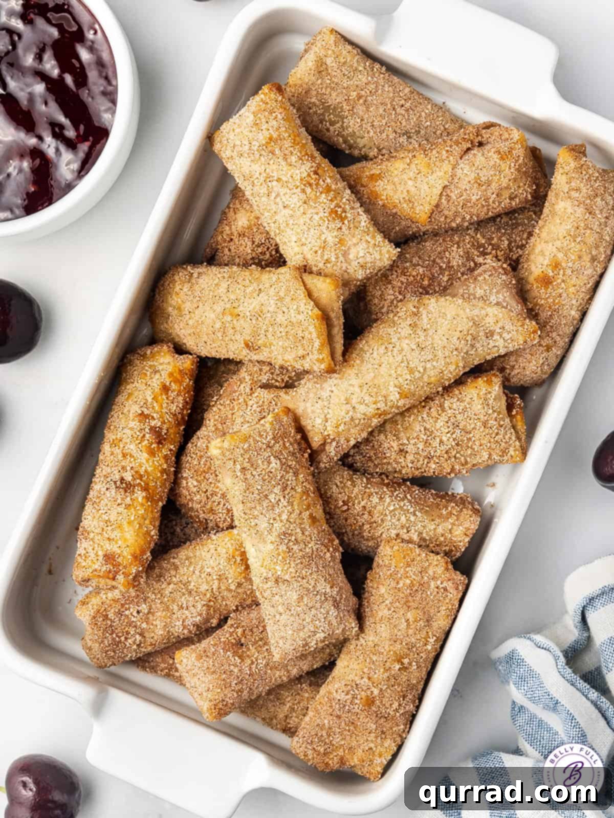 Overhead view of cherry cheesecake egg rolls in a baking dish