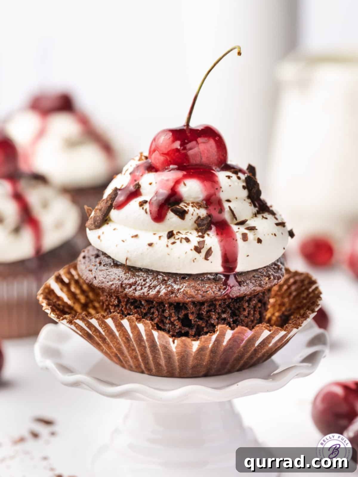 A black forest cupcake with the wrapper half pulled down