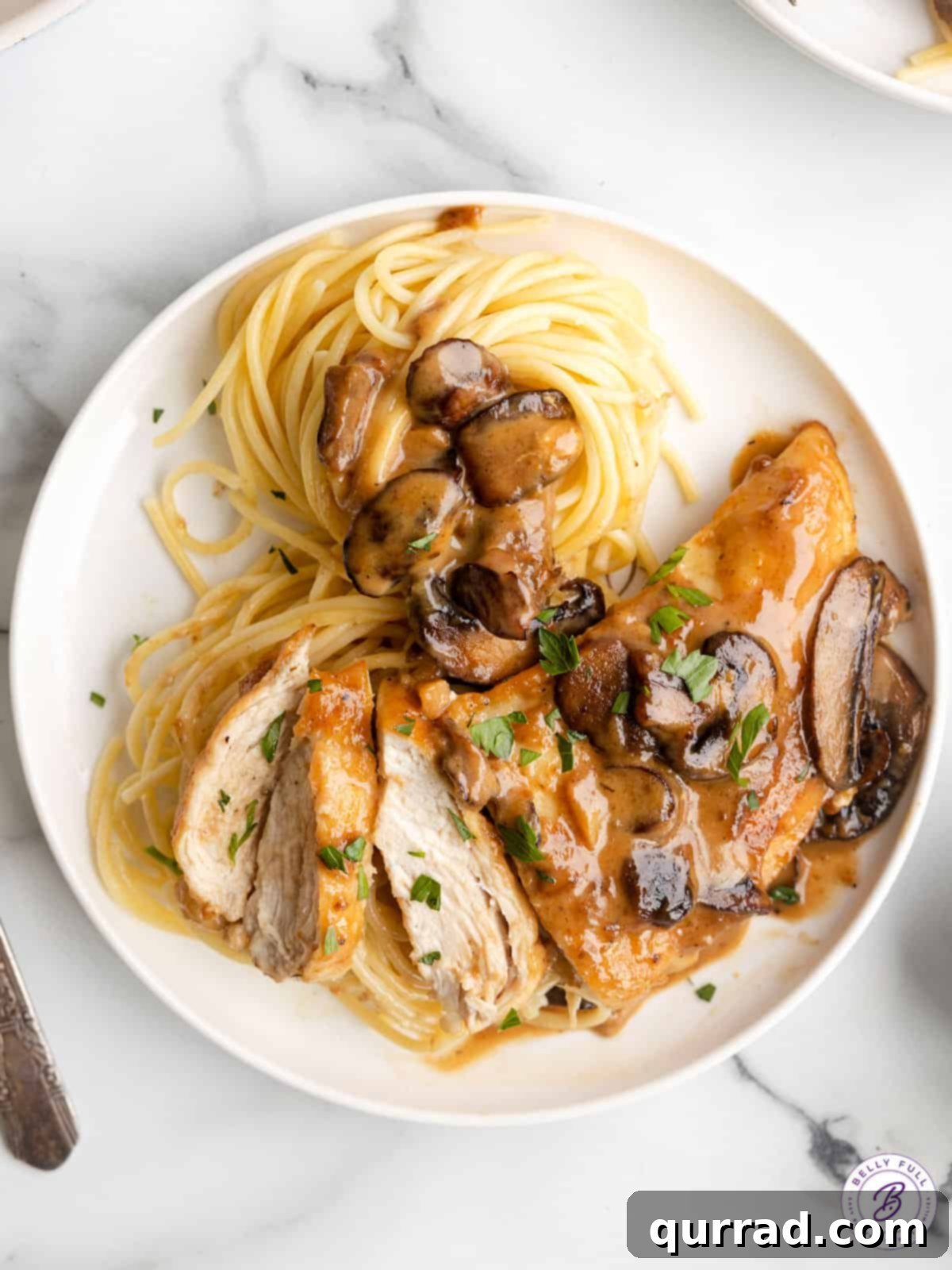 Overhead view of chicken marsala on a plate with spaghetti.